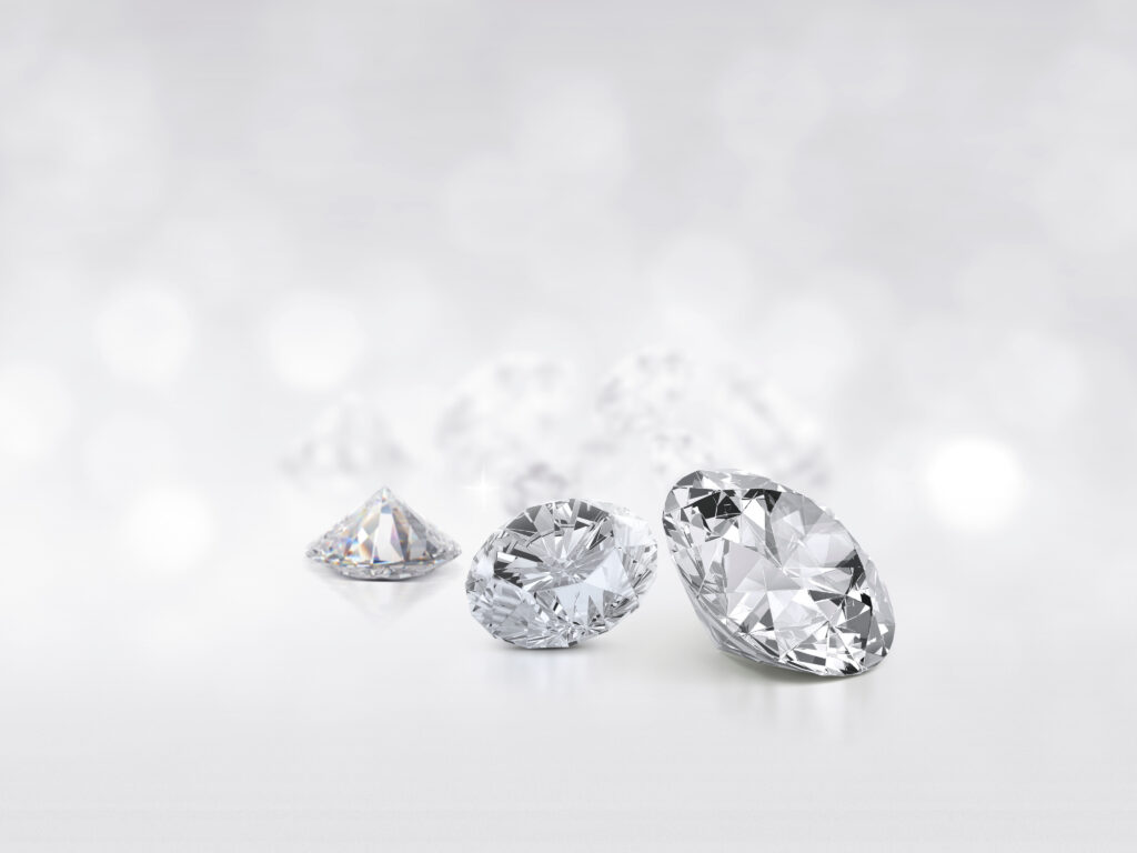 Drei lose Diamanten im Brillantschliff auf hellem Grund